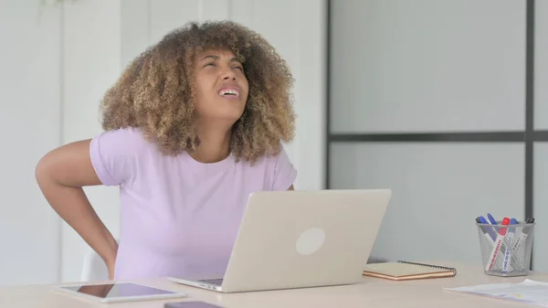 African American Woman having Back Pain while using Laptop in Office