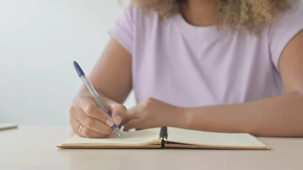 Close Up of African American Woman Writing on Notebook