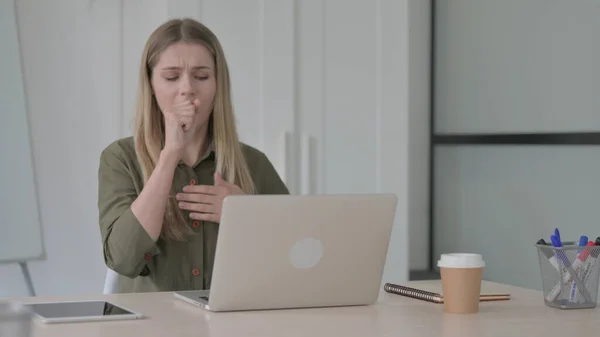 Blonde Young Woman Coughing while using Laptop in Office