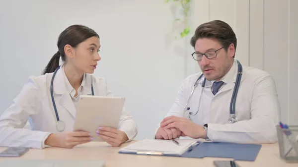 Female Doctor Discussing Medical Report with Senior Doctor