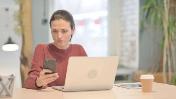 Mladá Žena Používající Smartphone Během Používání Notebooku — Stock fotografie