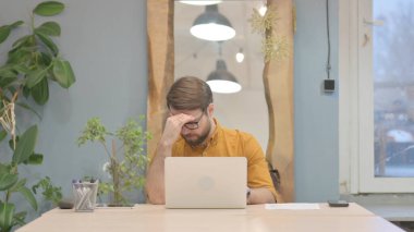 Orta yaşlı iş adamı dizüstü bilgisayarla uğraşırken baş ağrısı çekiyor