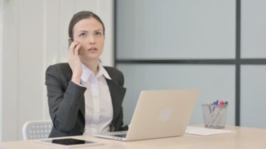 Displeased Businesswoman Talking Angrily on Smartphone at Work