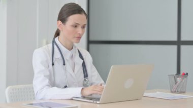 Young Doctor Smiling at Camera while using Laptop