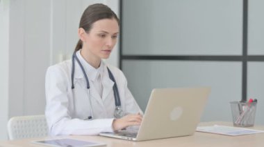 Thumbs Up by Young Doctor Working on Laptop