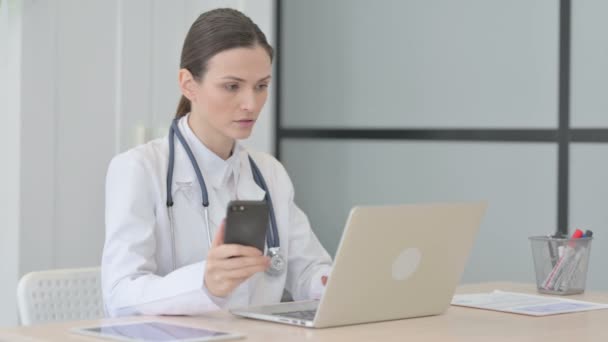 Νέος Γιατρός Χρησιμοποιώντας Smartphone Κατά Χρήση Laptop — Αρχείο Βίντεο