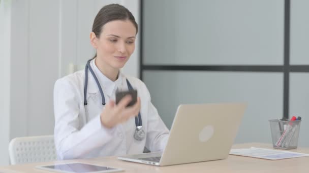 Νέος Γιατρός Μιλάει Στο Τηλέφωνο Ενώ Χρησιμοποιεί Laptop — Αρχείο Βίντεο
