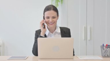 Genç İşkadını Laptop kullanırken telefonla konuşuyor