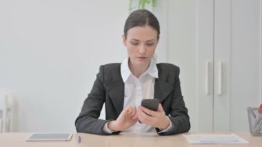 Young Businesswoman Browsing Internet on Smartphone in Office
