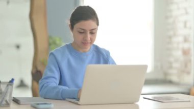 Dizüstü bilgisayar kullanırken kameraya bakan Hintli kadın