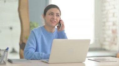 Laptop kullanırken telefonda konuşan Hintli kadın