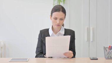 Young Businesswoman Reading Documents in Office, Paperwork