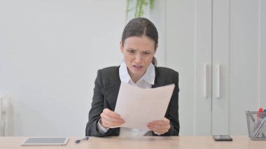 Young Businesswoman Upset by Loss while Reading Business Report