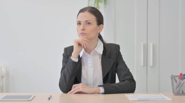 Pensive Young Businesswoman Thinking while Sitting at Work