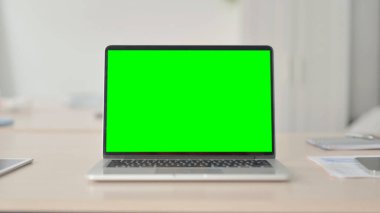 Laptop with Green Screen on Desk in Office