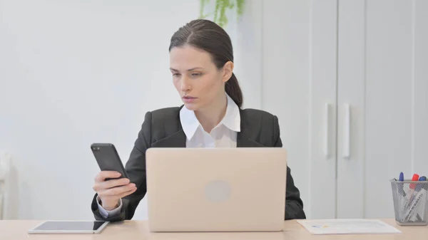 Young Businesswoman Using Smartphone While Using Laptop — Stock Fotó