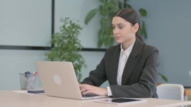 Young Businesswoman Leaving Office after Closing Laptop