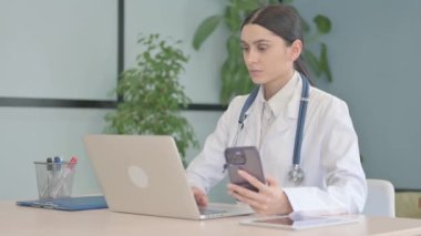 Genç Bayan Doktor Klinikte Laptop ve Smartphone üzerinde çalışıyor