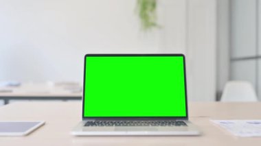 Laptop with Green Screen on Desk in Office