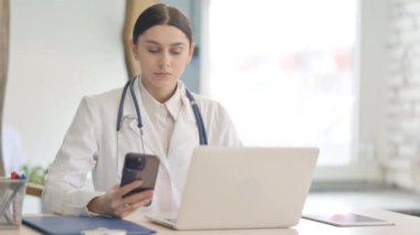 Genç Bayan Doktor Klinikte Laptop ve Smartphone üzerinde çalışıyor