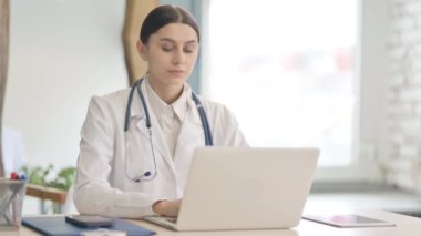 Genç Bayan Doktor Bilgisayarda çalışırken Kameraya Gülümsüyor