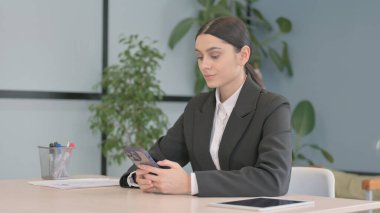 Genç Latin İş Kadını İş yerinde Akıllı Telefon Kullanıyor