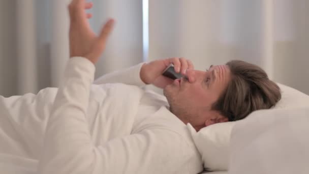床上电话中烦躁不安的成年男子的侧视图 — 图库视频影像