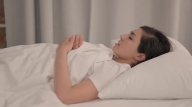 Yatakta yatarken öksüren genç kadının yan görüntüsü