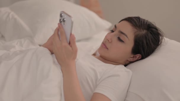 年轻女子躺在床上时使用智能手机 — 图库视频影像