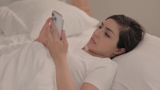 Młoda Kobieta Świętuje Sukces Smartfonie Leżąc Łóżku — Wideo stockowe