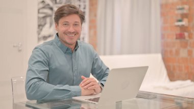 Yetişkin Adam Bilgisayarda Çalışırken Kameraya Gülümsüyor