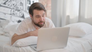 Genç Yetişkin Adam Laptop 'ta Video Sohbeti Yaparken Yatakta Mide Üzerine Yatıyor
