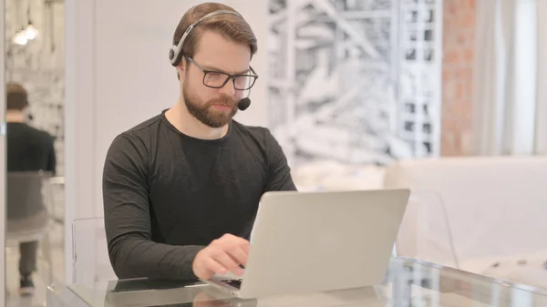 Hombre Adulto Joven Con Auriculares Que Trabajan Ordenador Portátil —  Fotos de Stock