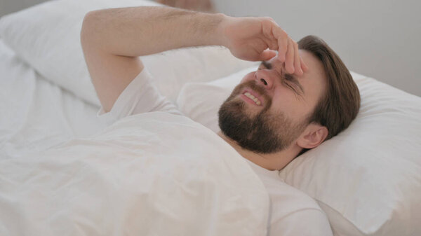 Young Adult Man with Headache Lying in Bed