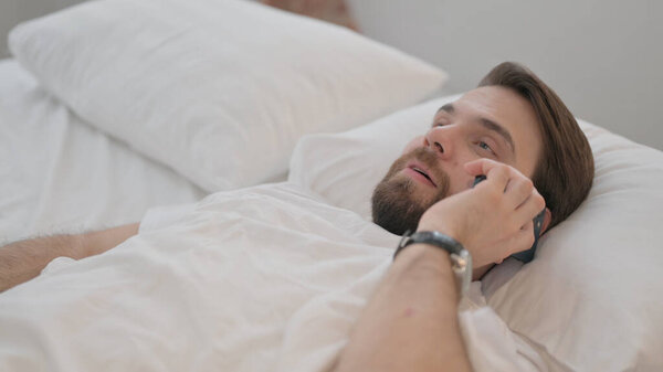 Young Adult Man Talking on Phone in Bed