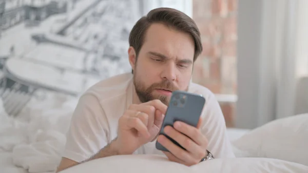 Homem Adulto Jovem Usando Smartphone Enquanto Deitado Estômago — Fotografia de Stock