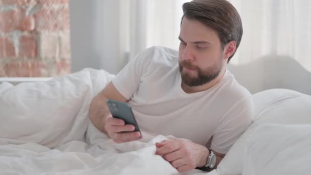 Giovane Uomo Adulto Sdraiato Sul Gomito Letto Utilizzando Telefono — Video Stock