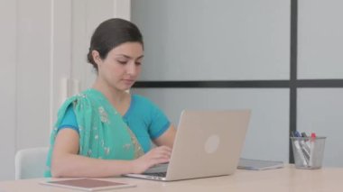 Bilgisayarda çalışırken kamerayı gösteren genç Hintli kadın.