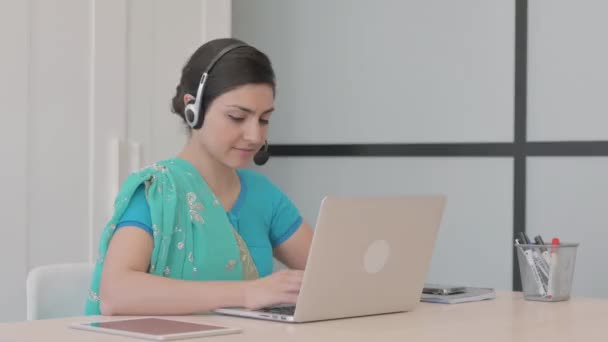 コールセンターでラップトップで働くヘッドセットを持つ若いインド人女性 — ストック動画