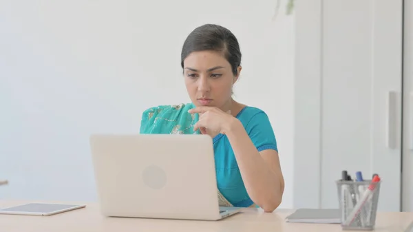 Pensive Indian Woman in Sari Working on Laptop