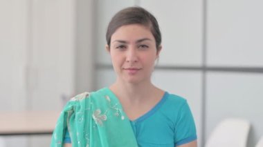 Sari 'de dudaklarında parmak olan Hintli kadının portresi.