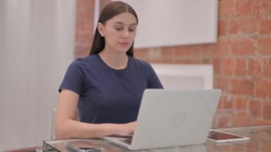 Laptop 'ta çalışırken kameraya gülümseyen genç Latin Kadın