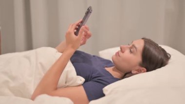 Yatakta Smartphone kullanan Genç Latin Kadın Görünümü