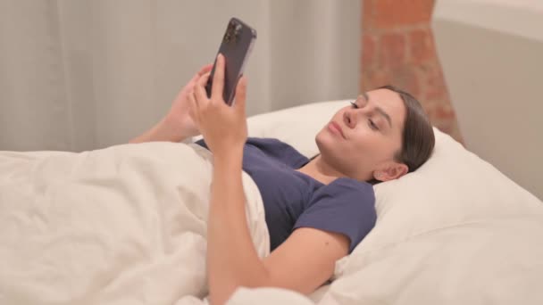 Ung Latinamerikansk Kvinna Firar Framgång Smartphone Sängen — Stockvideo