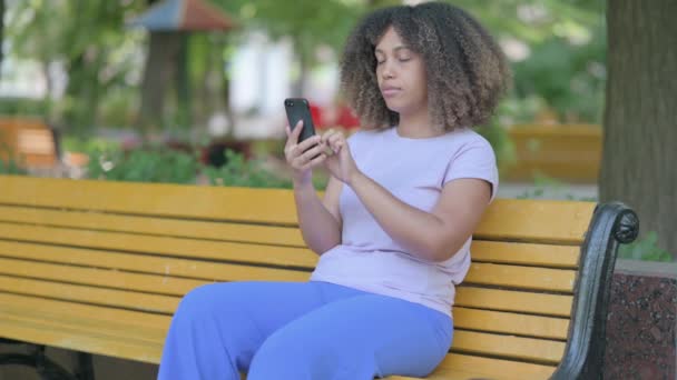 Upset Young African Woman Arguing Phone While Sitting Outdoor Bench — Stock Video