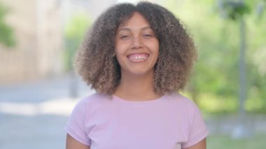 Kameraya bakan gülümseyen genç Afrikalı kadının açık hava portresi