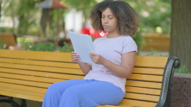 Joven Mujer Africana Leyendo Documentos Mientras Está Sentada Aire Libre — Vídeos de Stock
