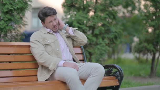 首の痛みと屋外に座って疲れ中年男 — ストック動画