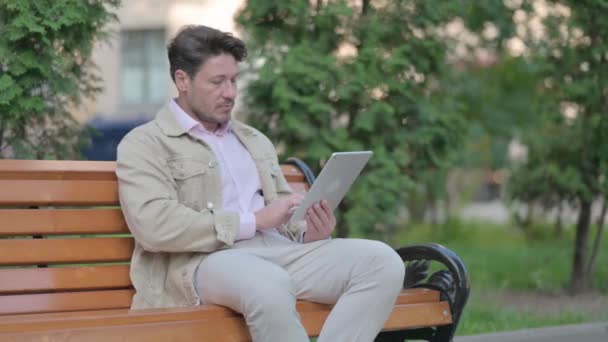 中年人坐在屋外的长椅上庆祝成功 — 图库视频影像