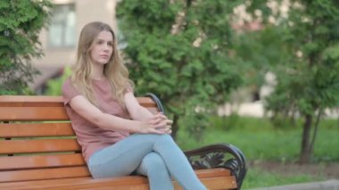 Bir bankta oturan sinirli genç kadın.